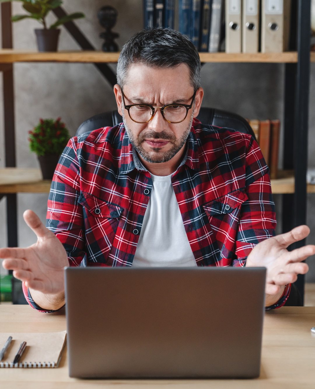Frustrated man sitting at the desk in home office using computer